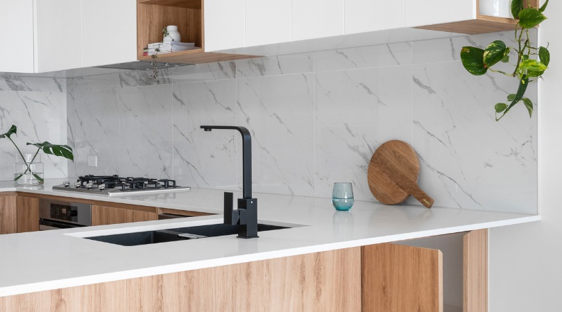 Kitchen bench with timber cabinets and black tap